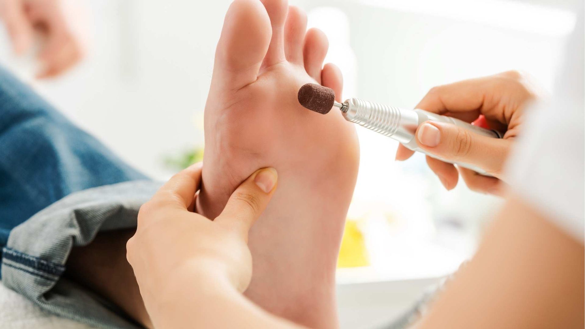 A person is getting their feet polished by a nail technician.