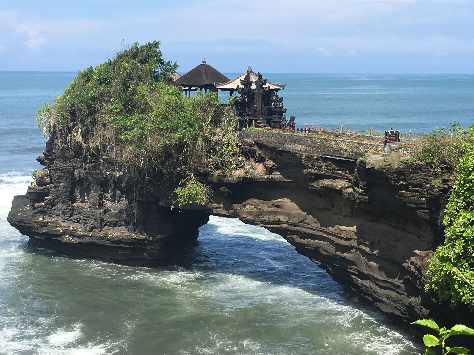 Rock formation with arch over ocean, topped with a Balinese temple.