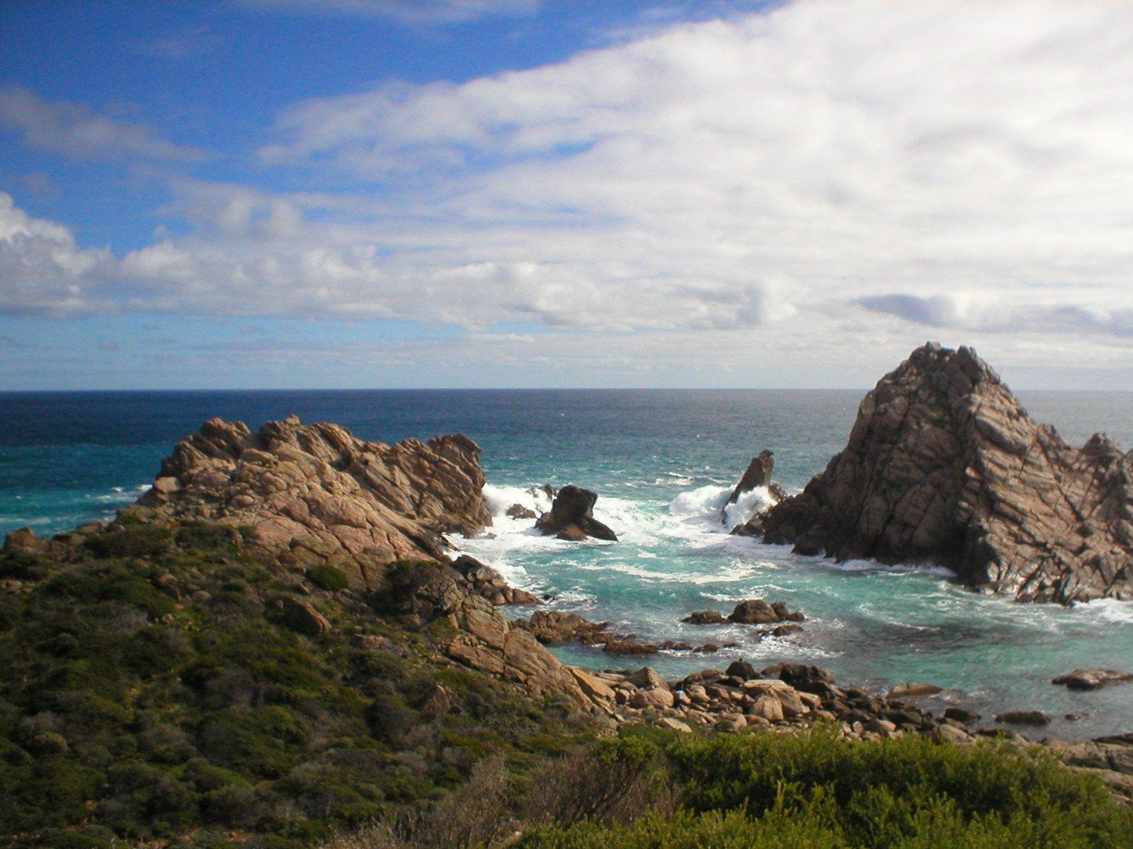 Rocky coastline with turquoise water under a blue sky and white clouds. - Adult Therapy on Wurtulla, QLD