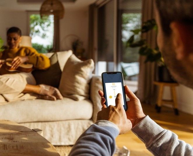 Un homme est assis sur un canapé en train d'utiliser un téléphone intelligent.