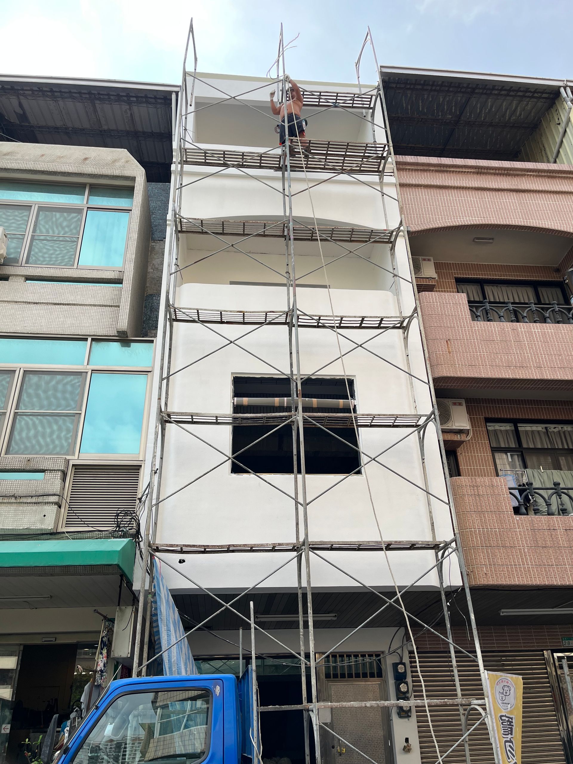 一輛藍色卡車停在一棟正在興建的建築物前。