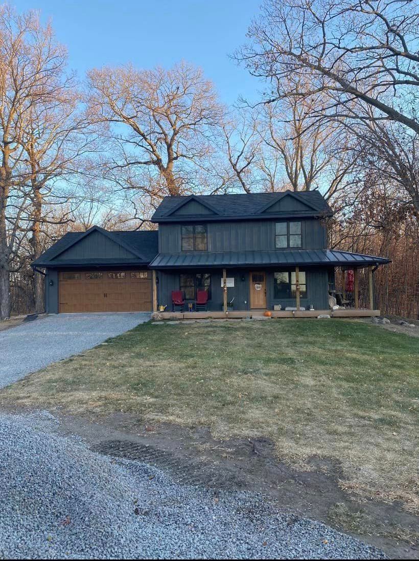 A black house with a garage and a driveway in front of it.