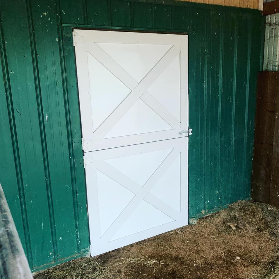 A white door in a barn with a green wall