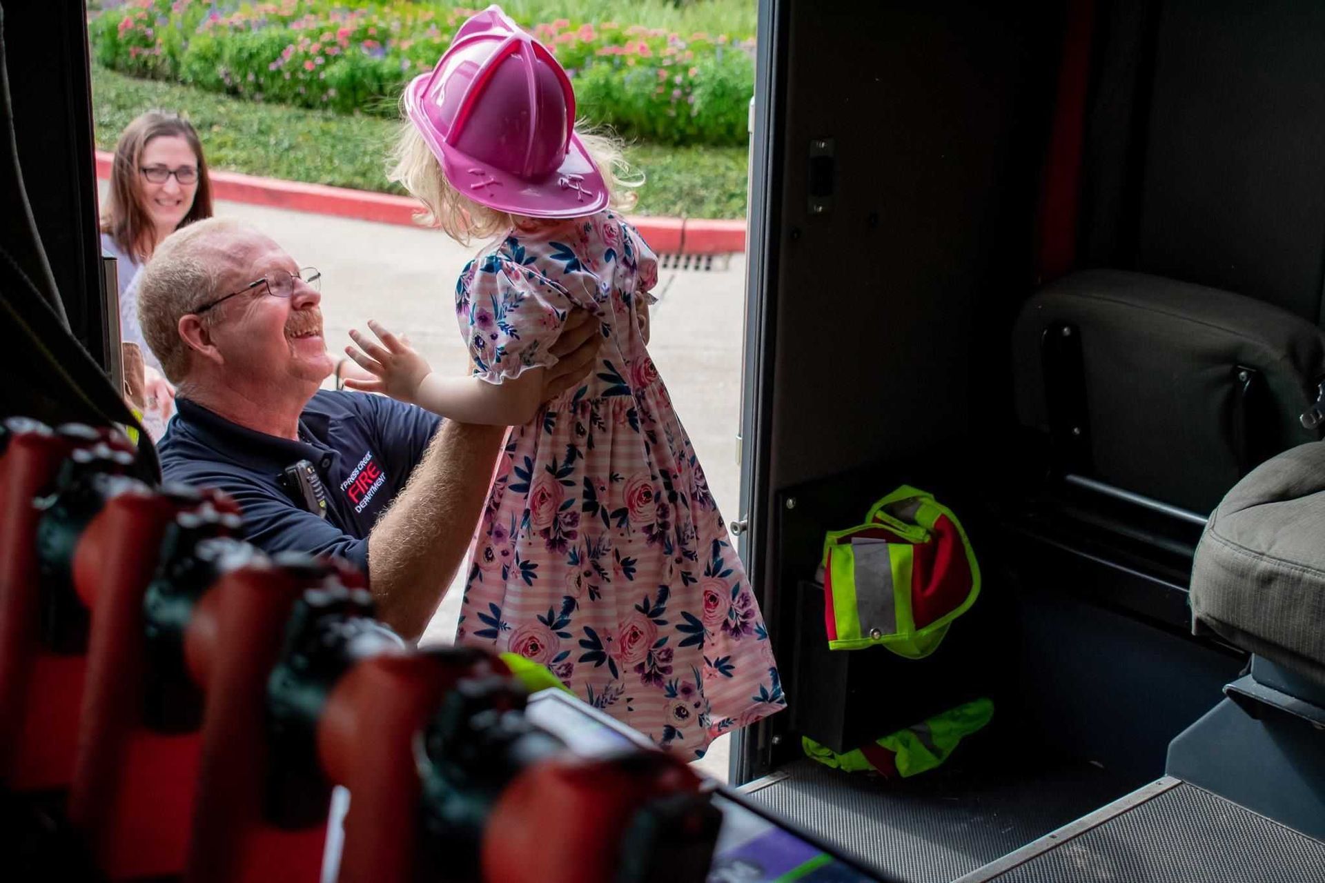 A man is holding a little girl in a pink hat in his arms.