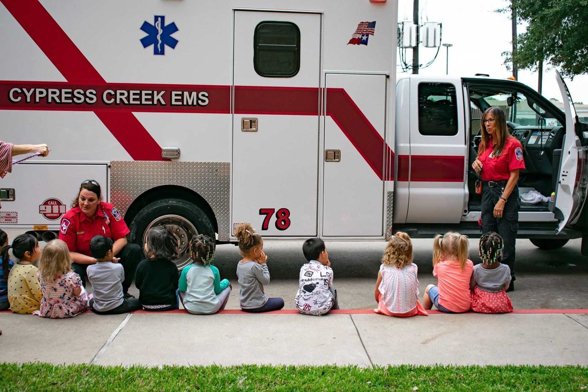 Two Cypress Creek Fire personnel standing next to each other with one holding a fire helmet that says emergency