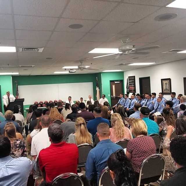 A large group of people are sitting in a room watching a firefighter graduation ceremony.