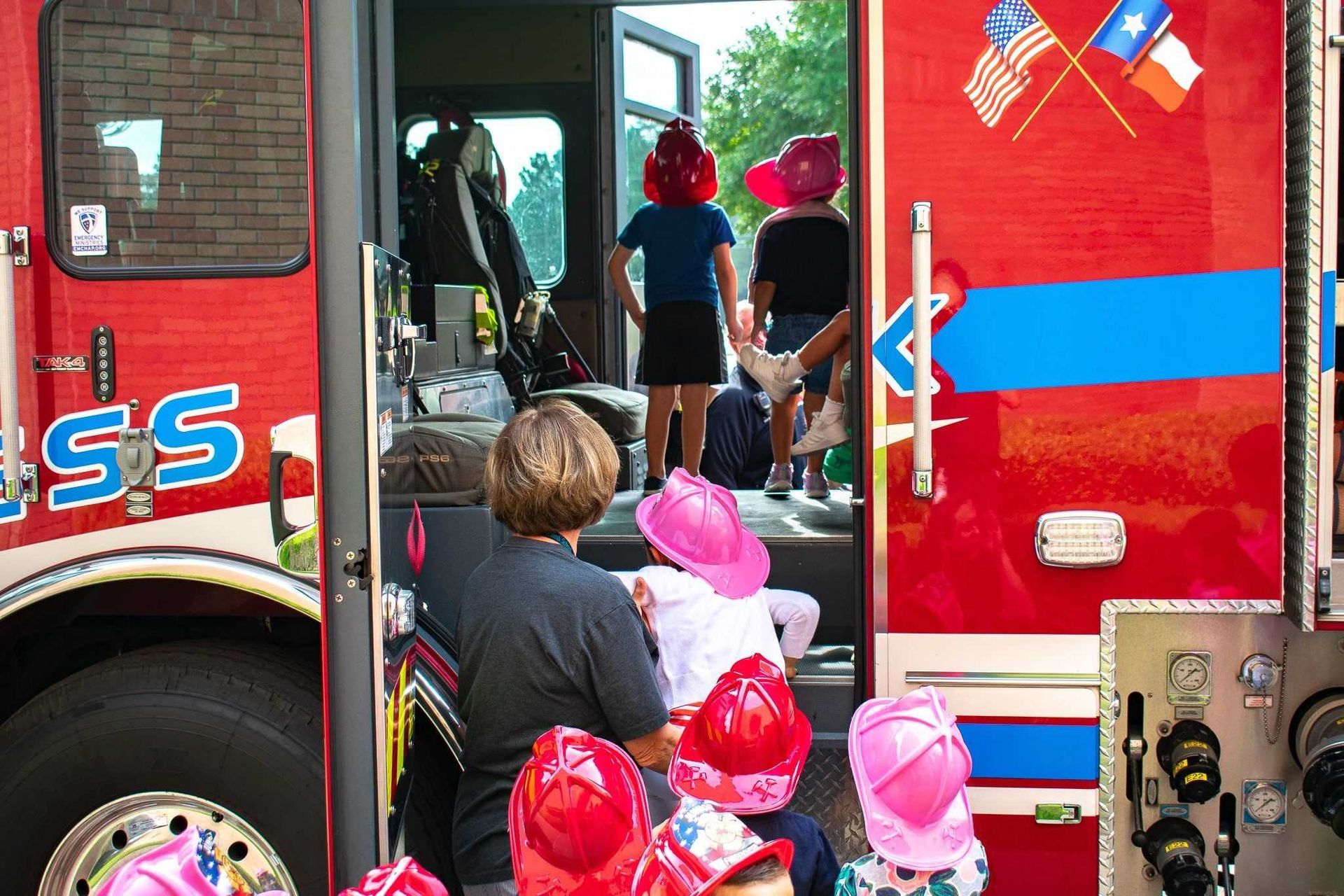 A group of children are sitting in the back of a fire truck.