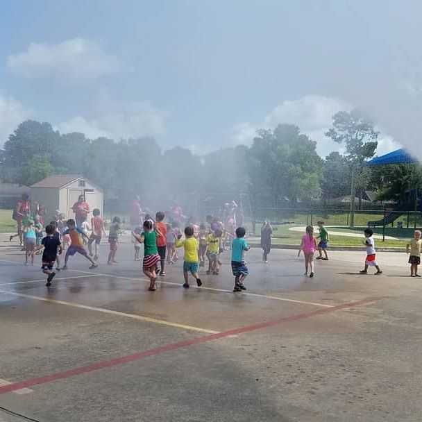 A group of children are running through a spray park.