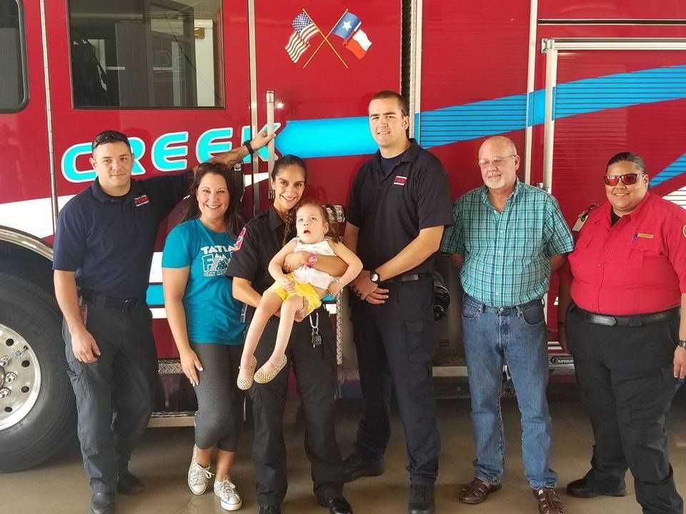 A group of people standing in front of a fire truck that says creek