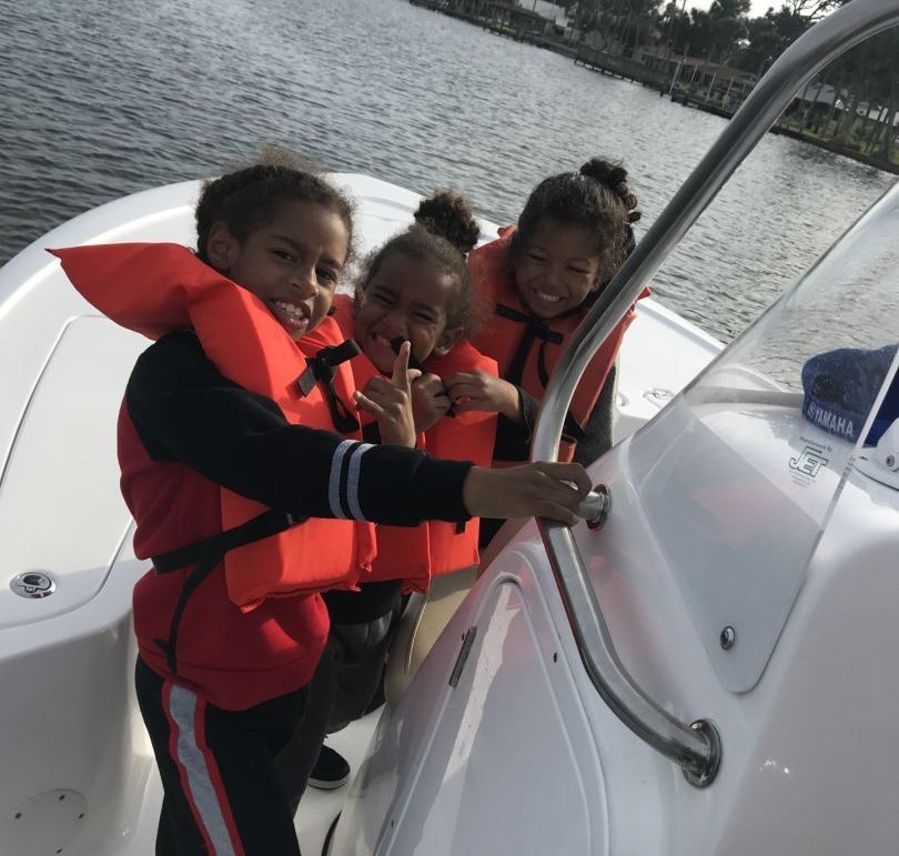 Three children wearing life jackets are on a boat