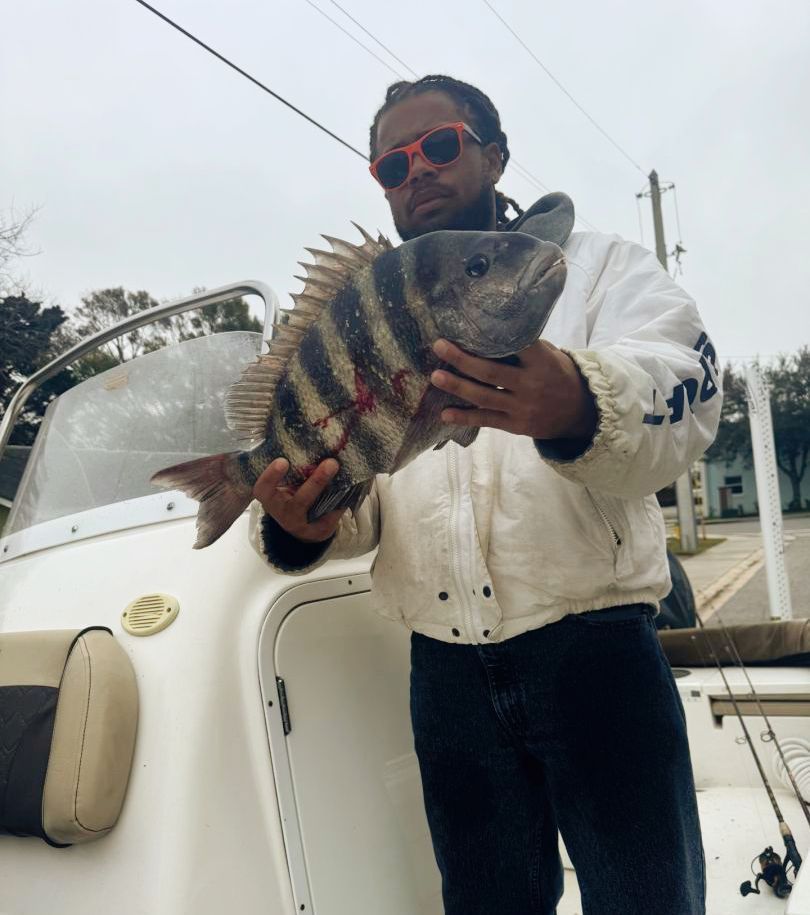 A man is holding a large fish in front of a boat