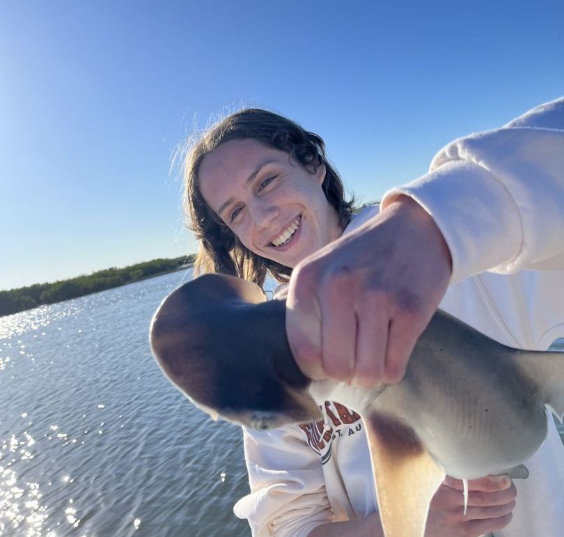 A woman is holding a shark in her hands and smiling