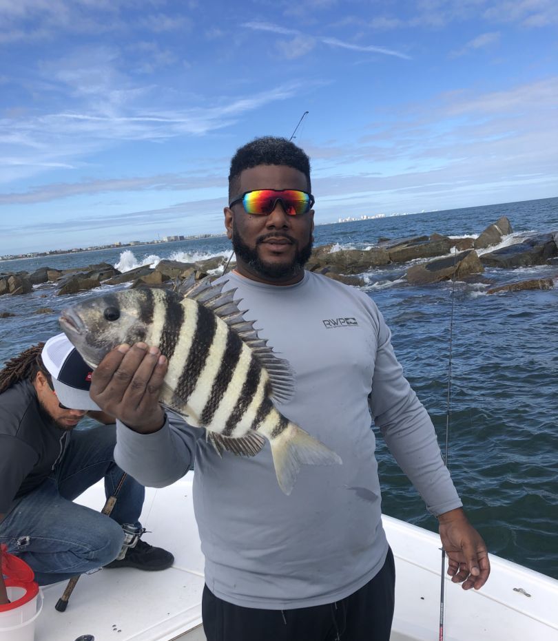 A man is holding a striped fish on a boat.