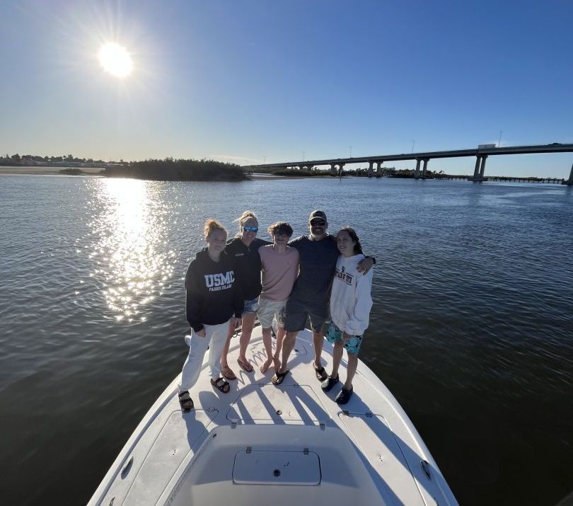 A group of people are posing for a picture on the back of a boat.