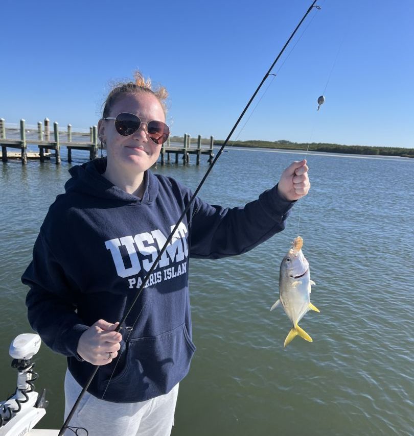 A woman wearing a usm sweatshirt is holding a fish