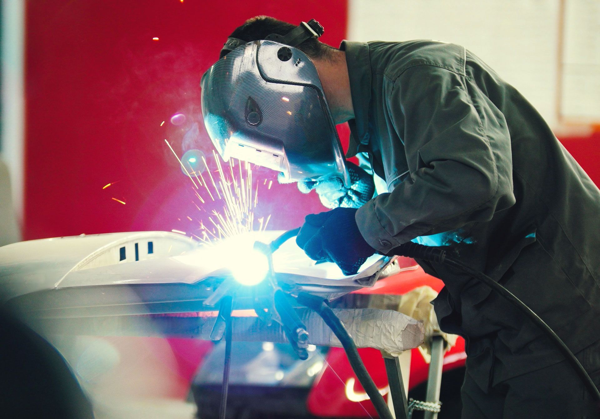 A man is welding a car in a garage .
