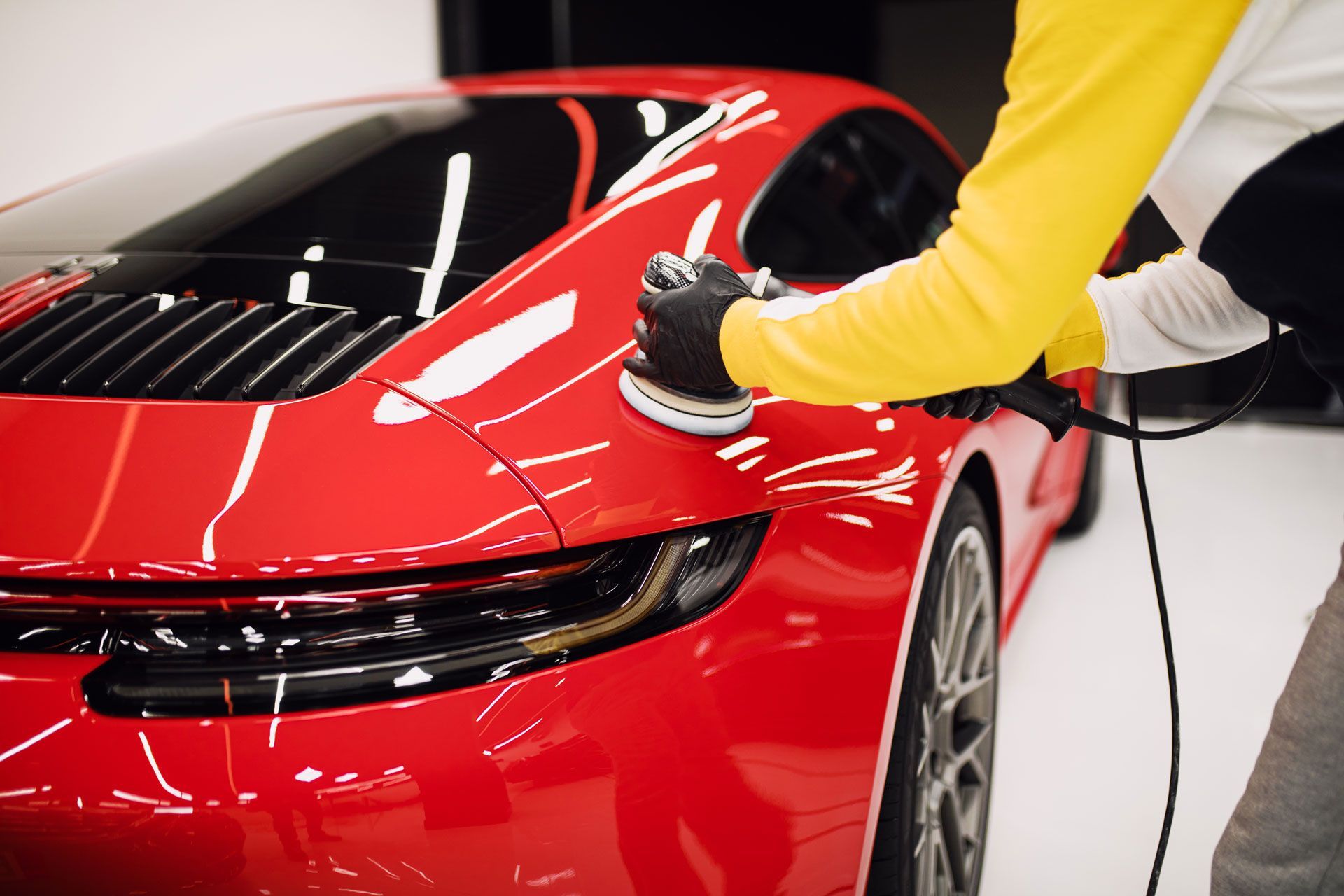 A man is polishing a red sports car with a machine .