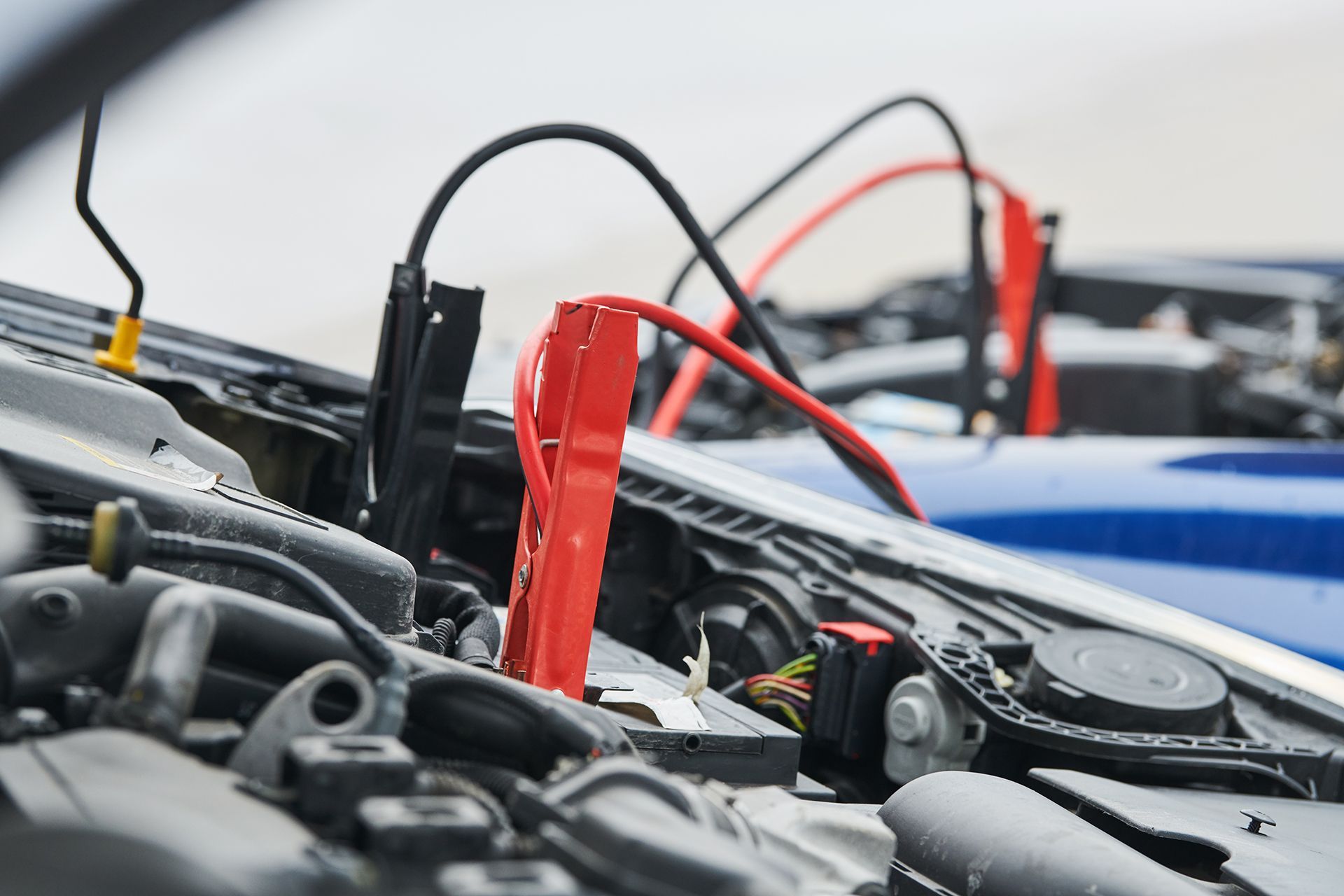A close up of a car engine with jumper cables attached to it.
