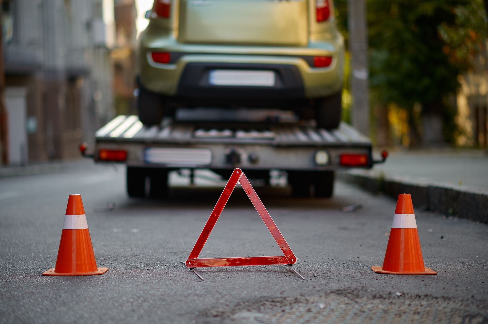 A car is being towed down the street by a tow truck.