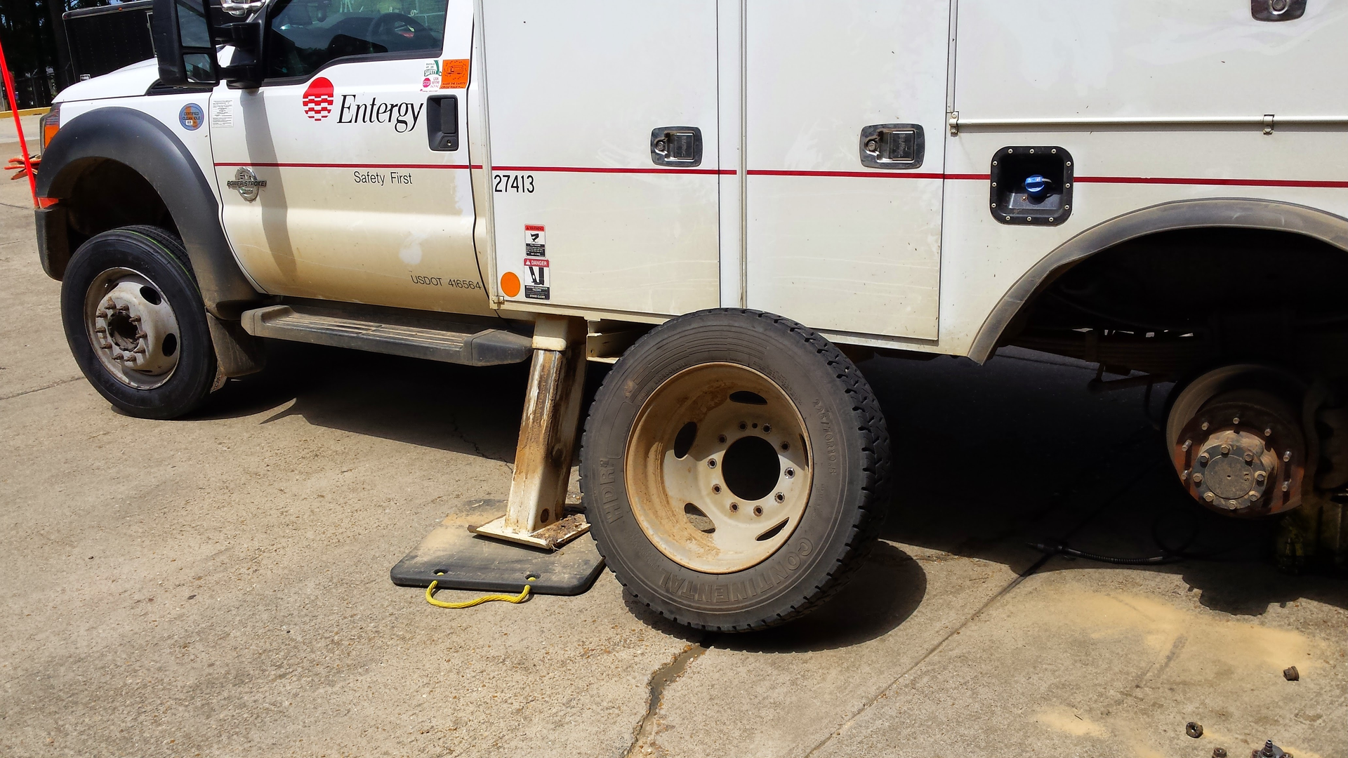 A man is holding a tire in front of a broken down car.