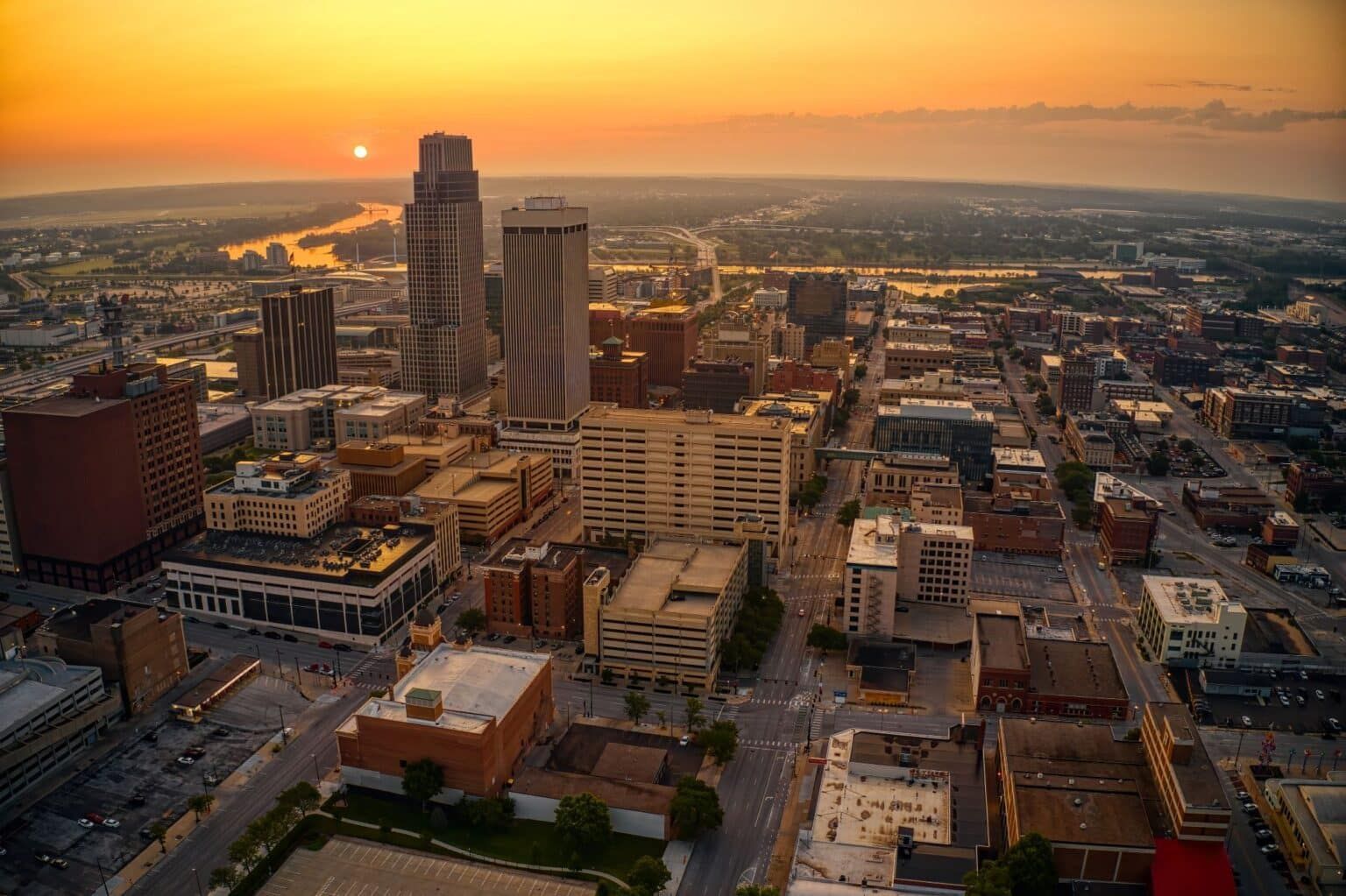 Aerial view of the Omaha skyline at sunset, featuring the WoodmenLife Tower and the Missouri River in the distance.