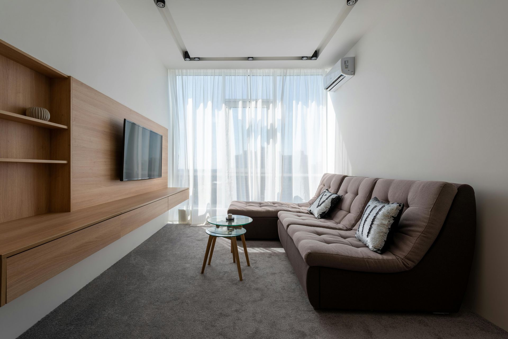 Modern white kitchen with wooden countertops, gray flooring, two windows, and hanging pendant lights over a small table.