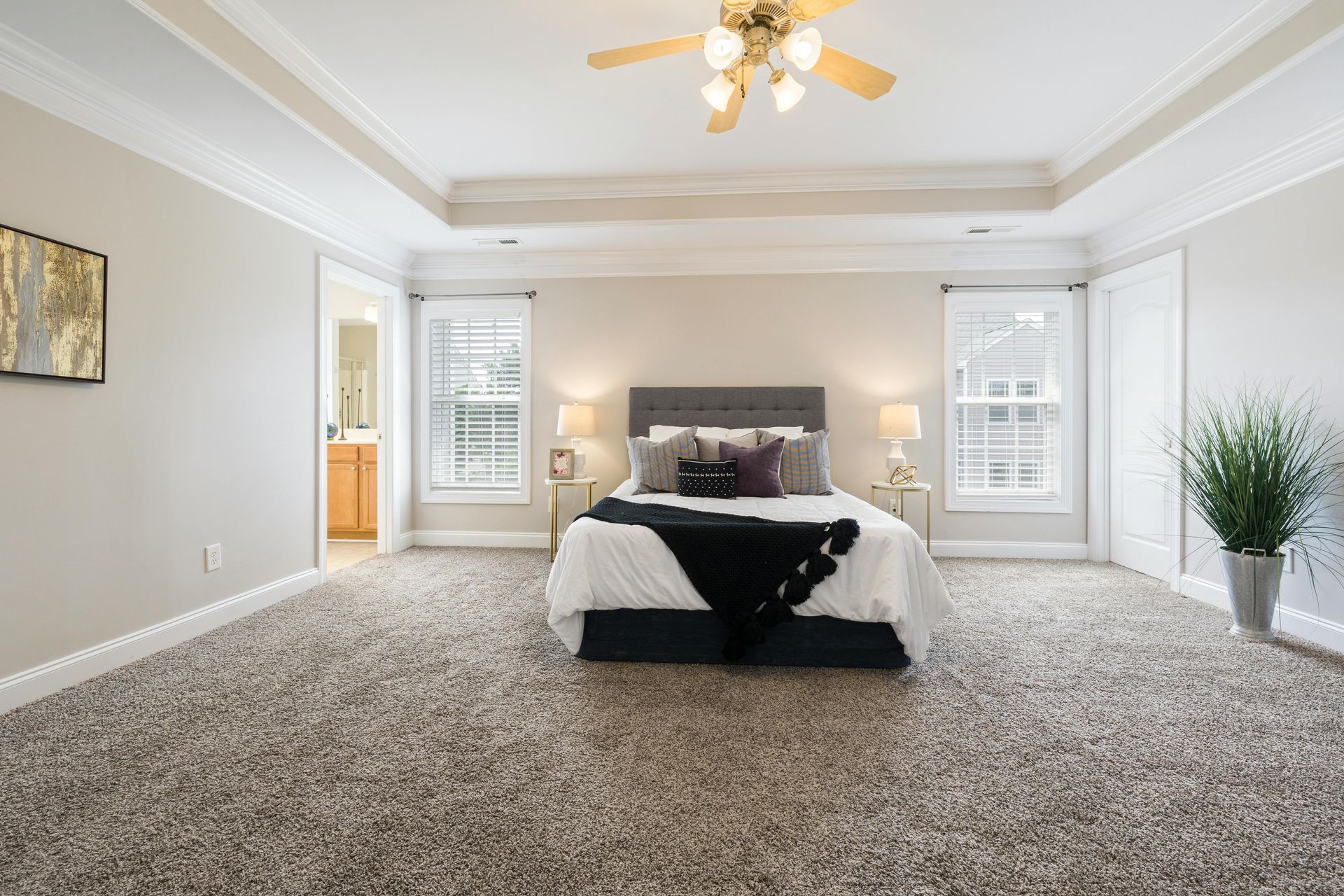 A modern living room with hardwood floors, a dark sofa, a coffee table, and large windows overlooking autumn trees.