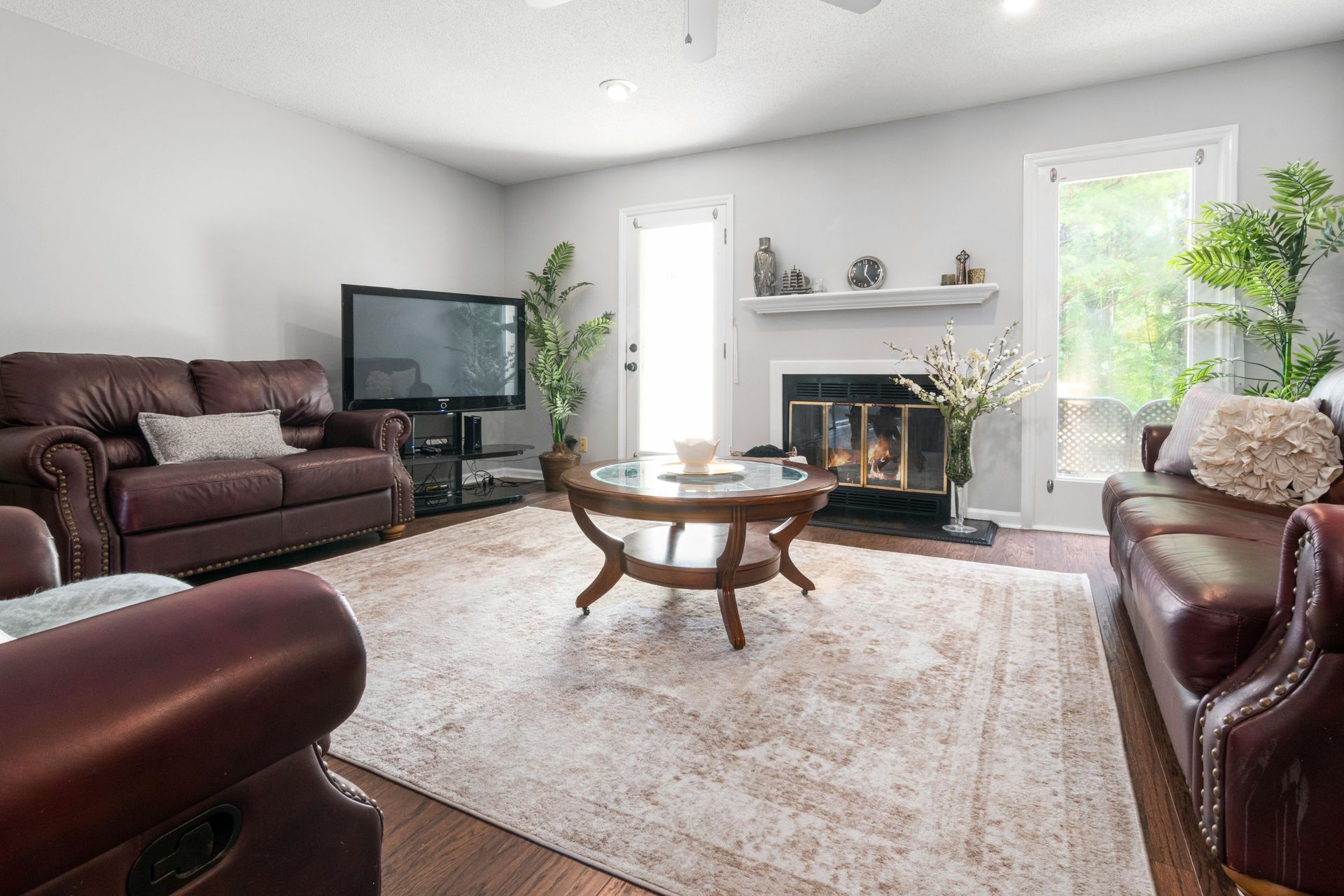 Modern white kitchen with wooden countertops, gray flooring, two windows, and hanging pendant lights over a small table.