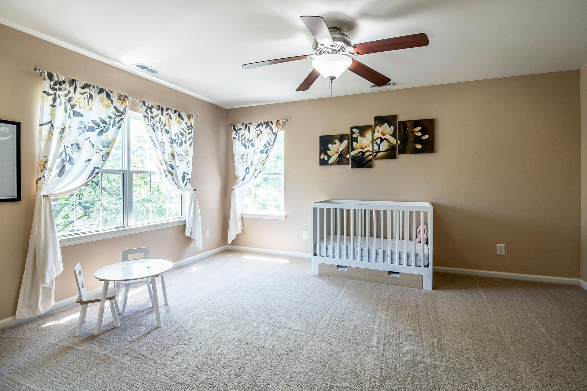 A modern living room with hardwood floors, a dark sofa, a coffee table, and large windows overlooking autumn trees.