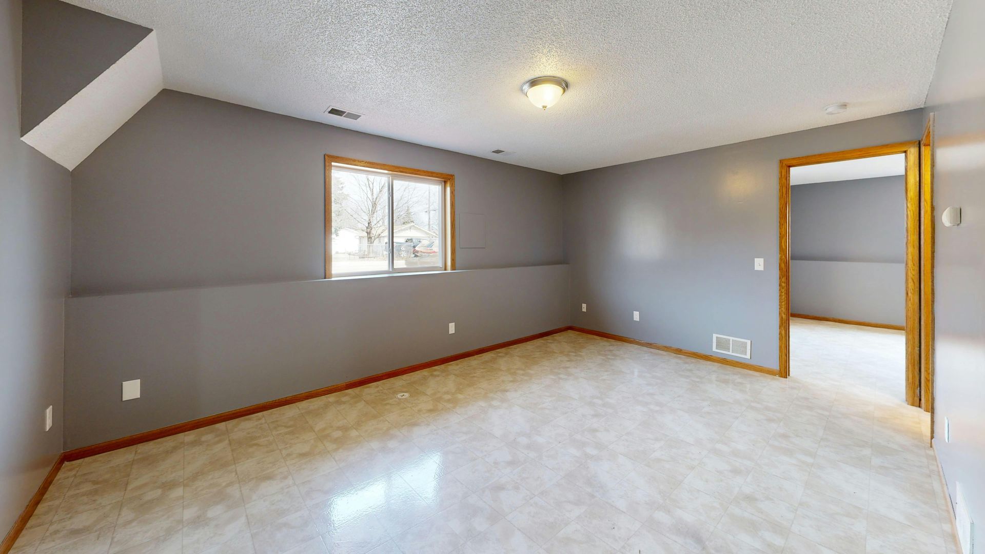 A modern, empty conference room with a long table, ergonomic black chairs, and light-toned wood flooring and wall panels.