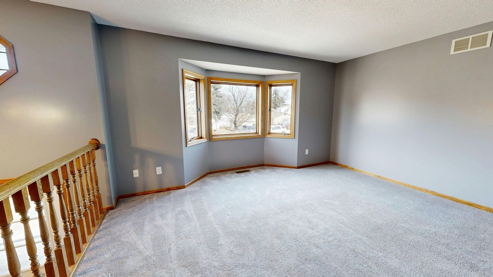 Modern white kitchen with wooden countertops, gray flooring, two windows, and hanging pendant lights over a small table.