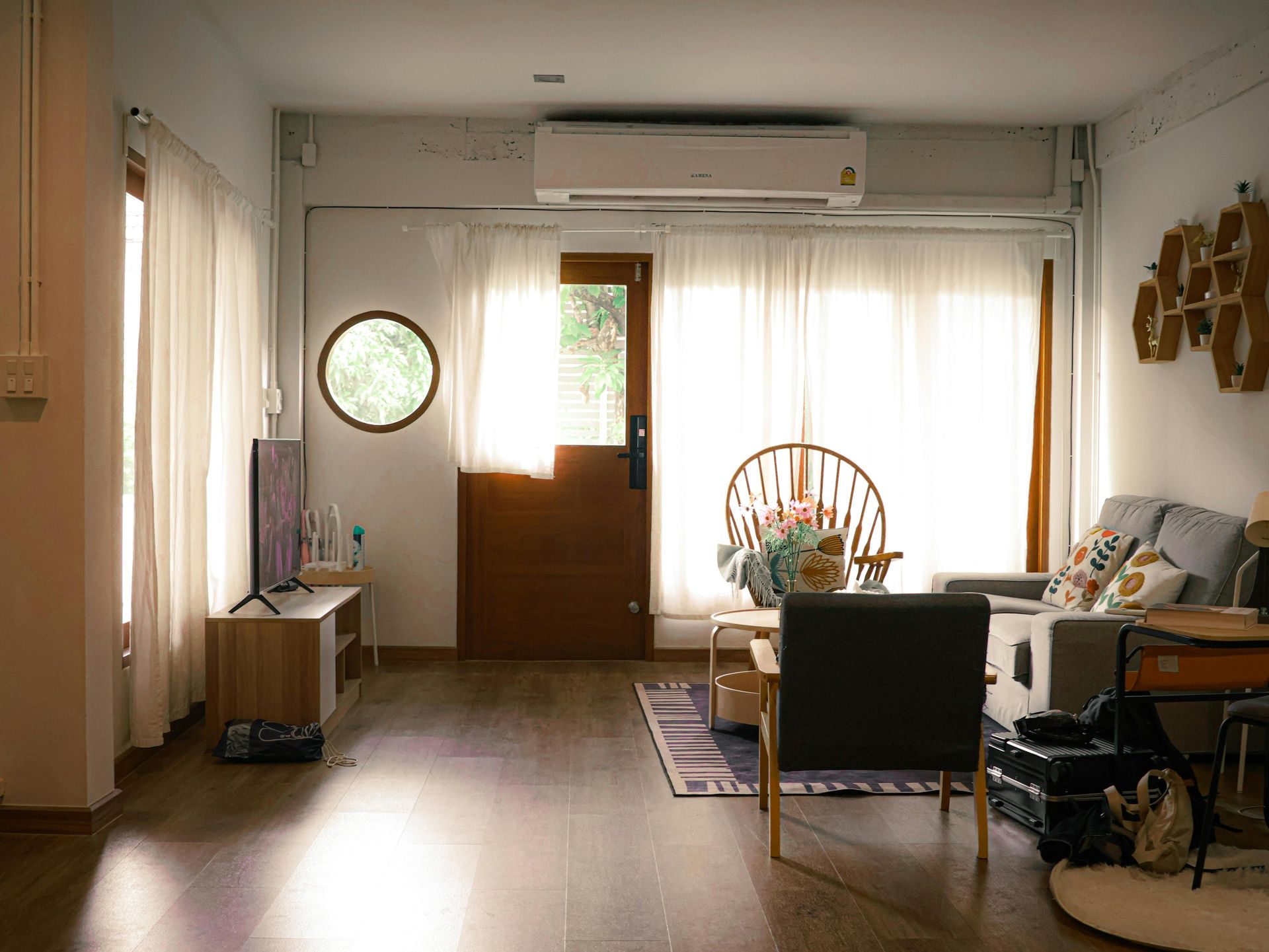 Modern white kitchen with wooden countertops, gray flooring, two windows, and hanging pendant lights over a small table.