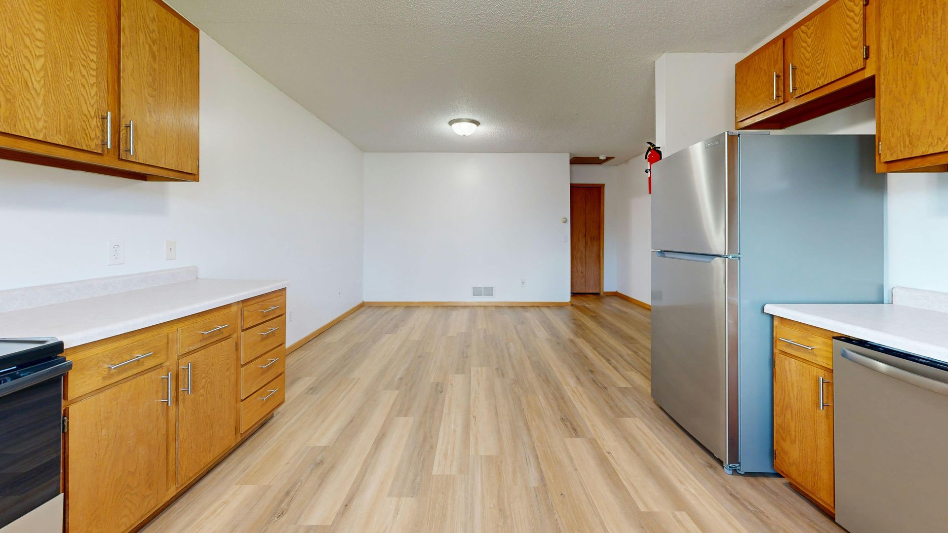 A modern living room with hardwood floors, a dark sofa, a coffee table, and large windows overlooking autumn trees.