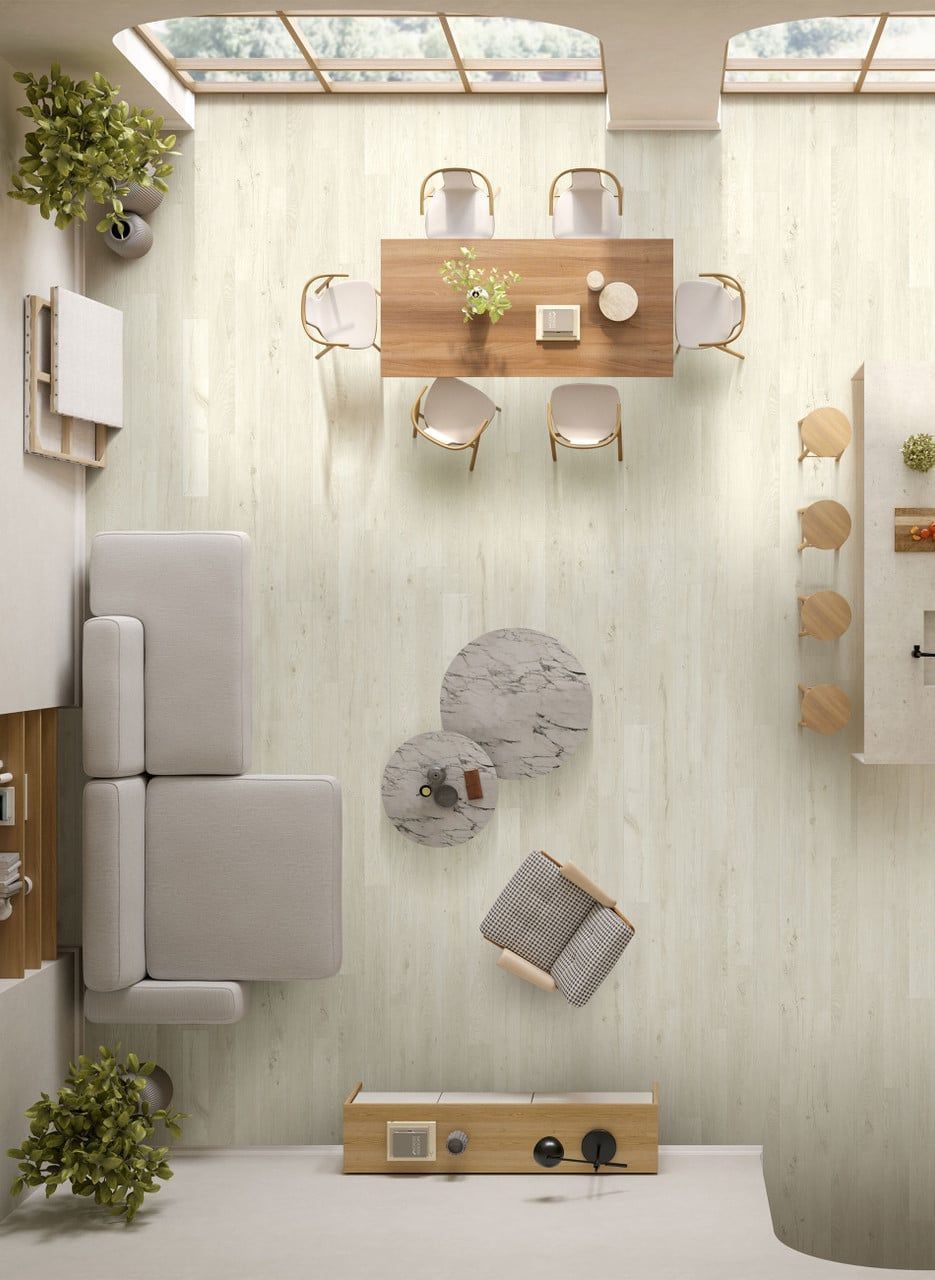 Top-down view of a bright, modern living and dining space with light wood flooring, a table for six, and modular seating.