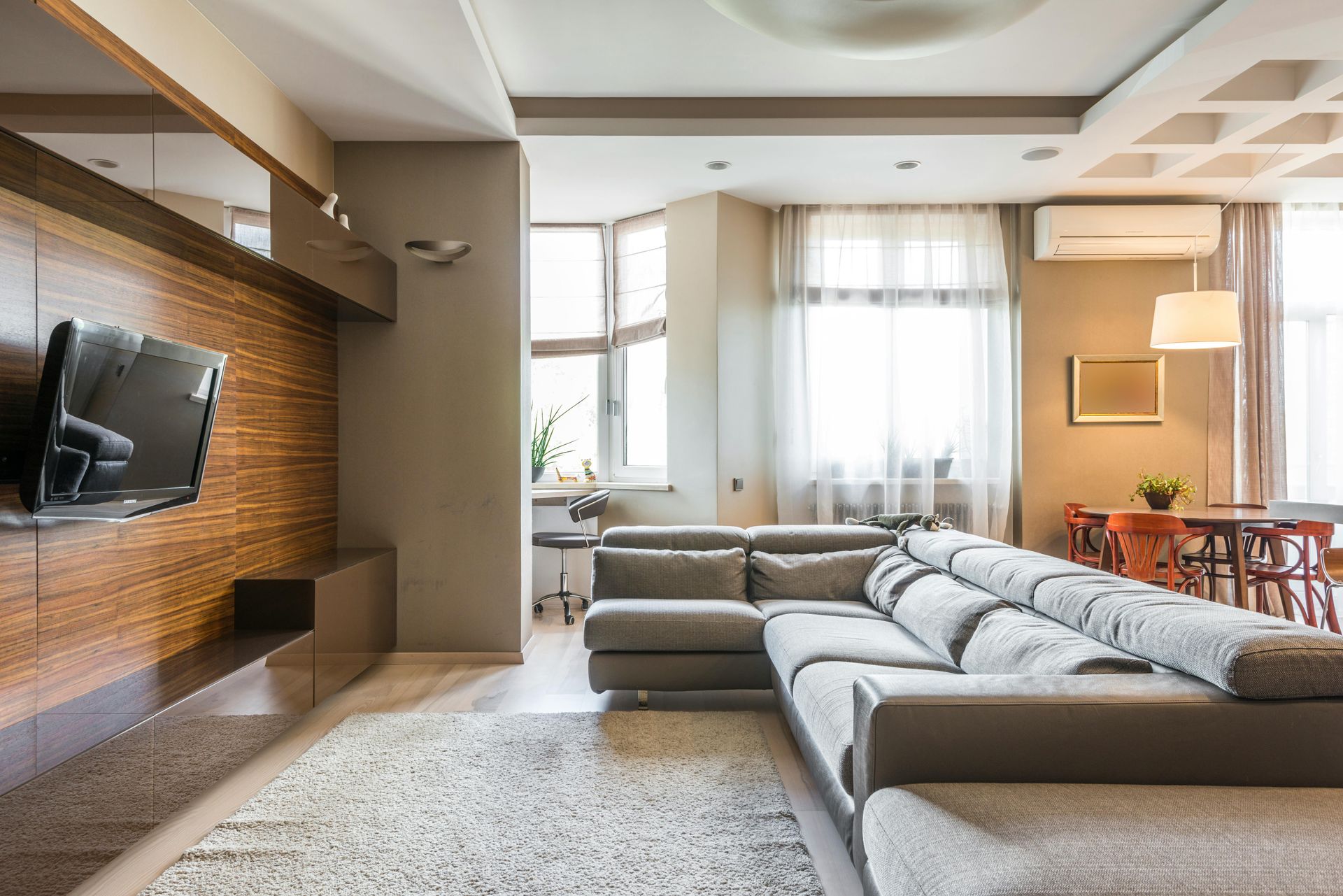 A modern, empty conference room with a long table, ergonomic black chairs, and light-toned wood flooring and wall panels.