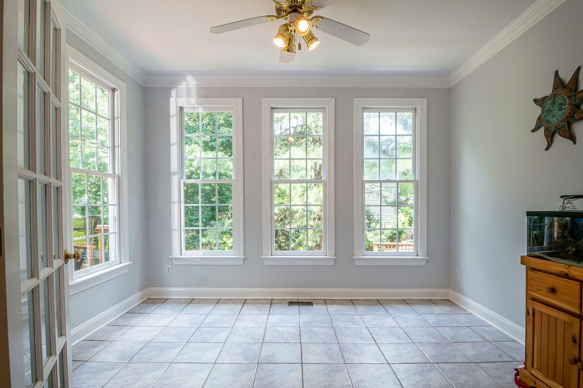 Modern white kitchen with wooden countertops, gray flooring, two windows, and hanging pendant lights over a small table.
