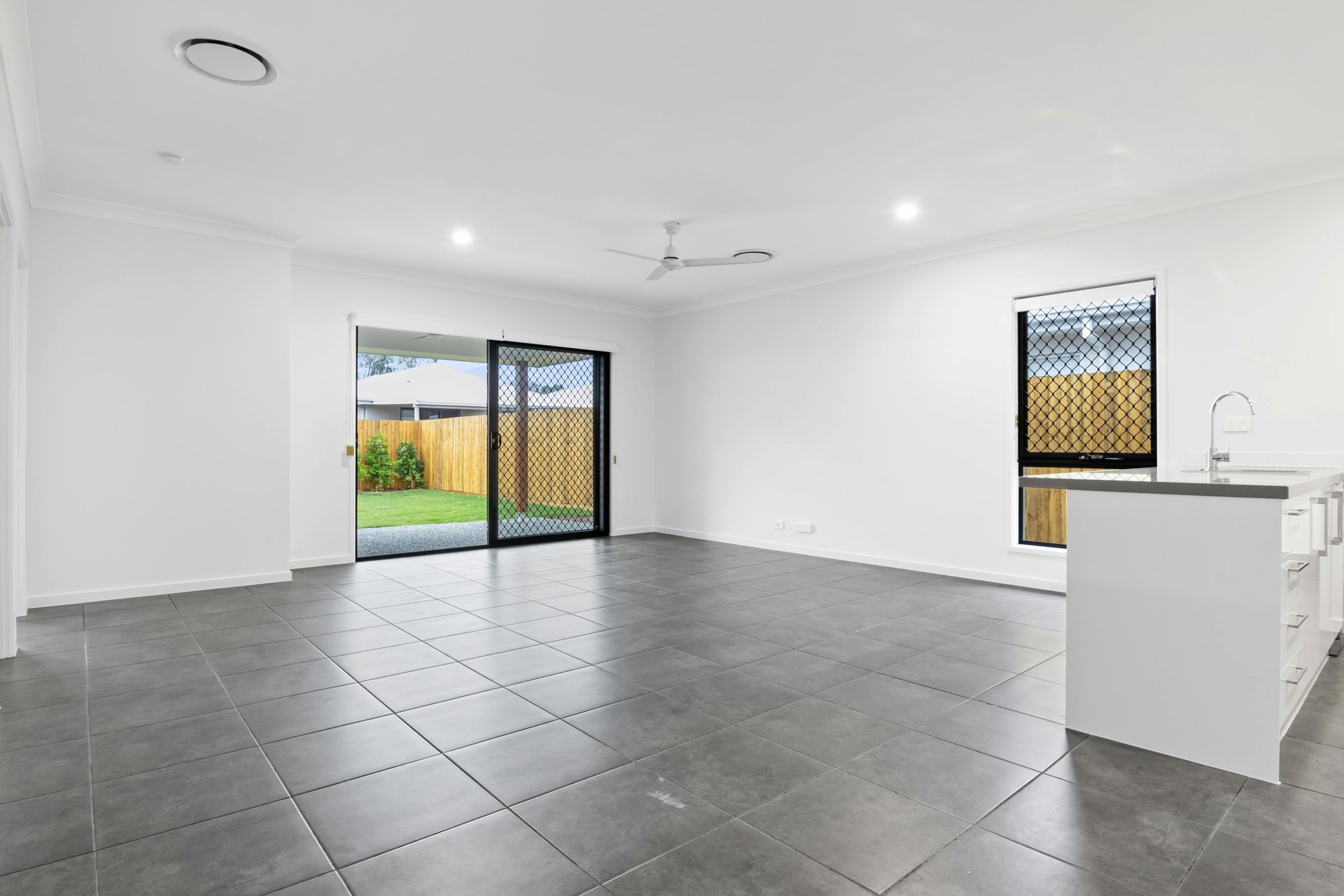 A modern, empty conference room with a long table, ergonomic black chairs, and light-toned wood flooring and wall panels.
