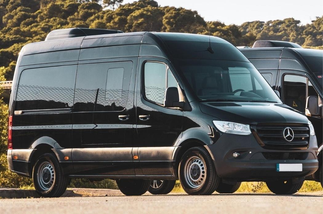 Dos furgonetas negras están estacionadas una al lado de la otra al costado de la carretera.
