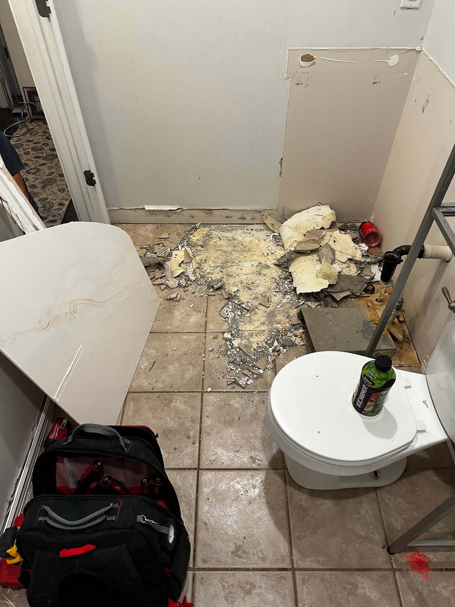 A bathroom with a toilet and a bag on the floor.