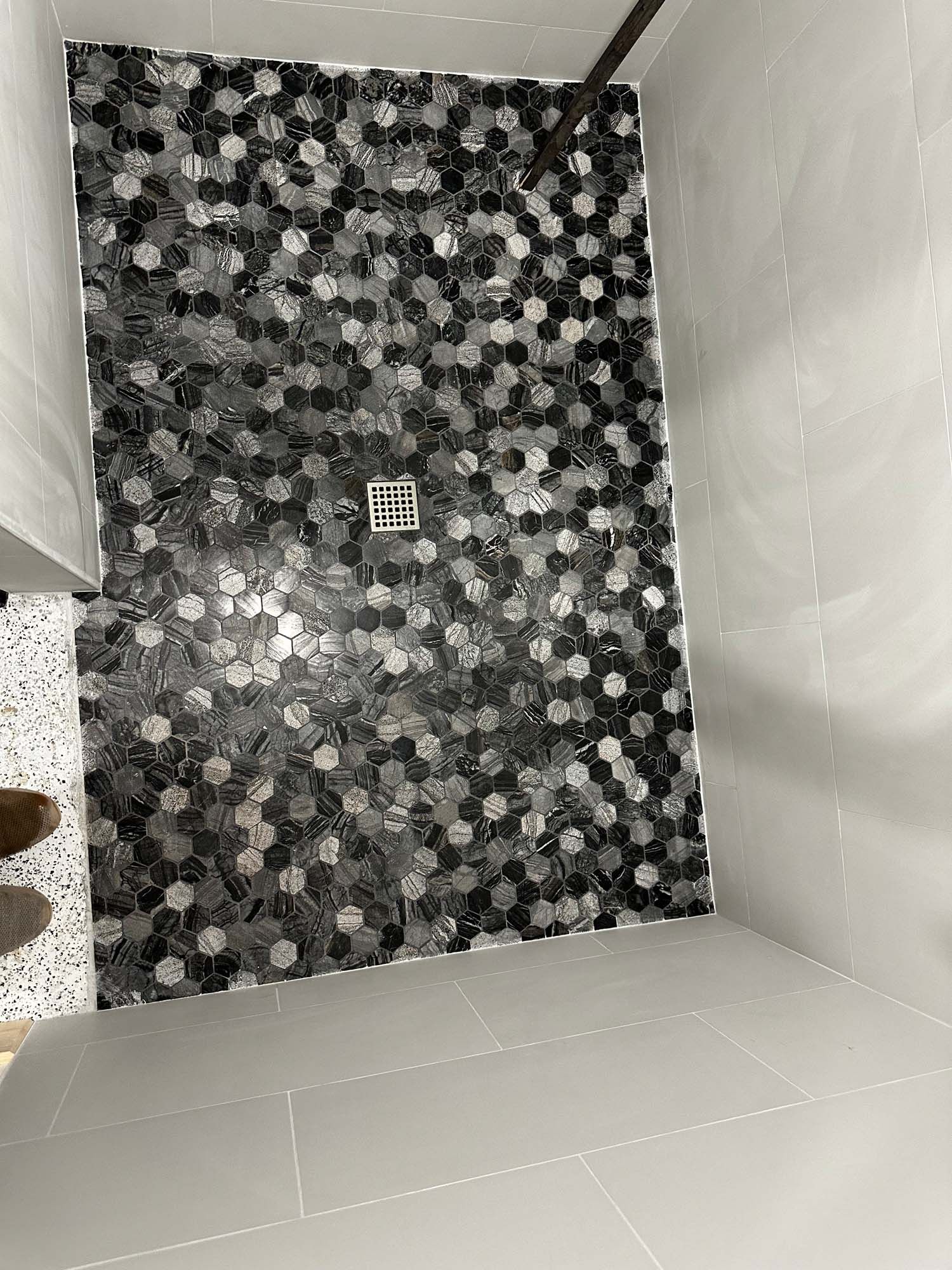 A black and white photo of a shower stall with a drain.
