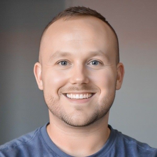 Woman with slicked-back hair, hoop earrings, and orange-toned makeup against an orange background.