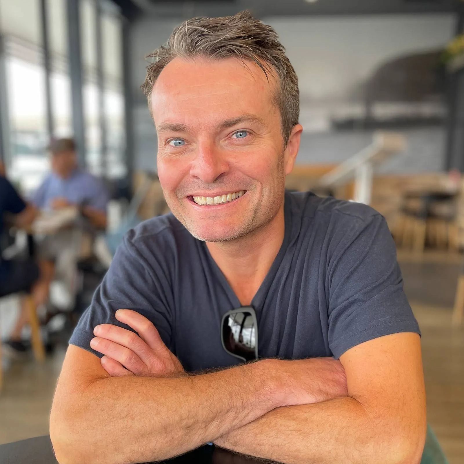 Woman with slicked-back hair and large gold hoop earrings, facing the camera with a warm glow.