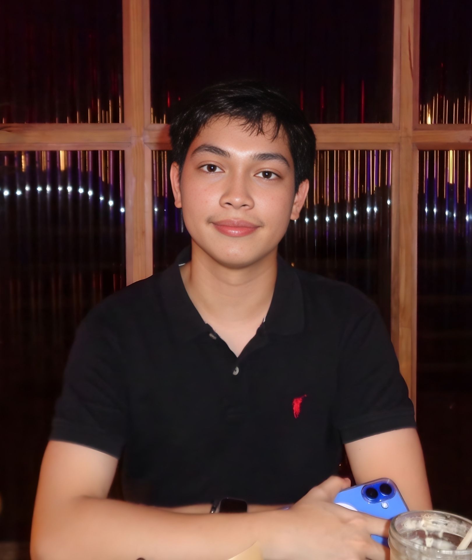 Woman with slicked-back hair and large hoop earrings, posing in front of an orange background.