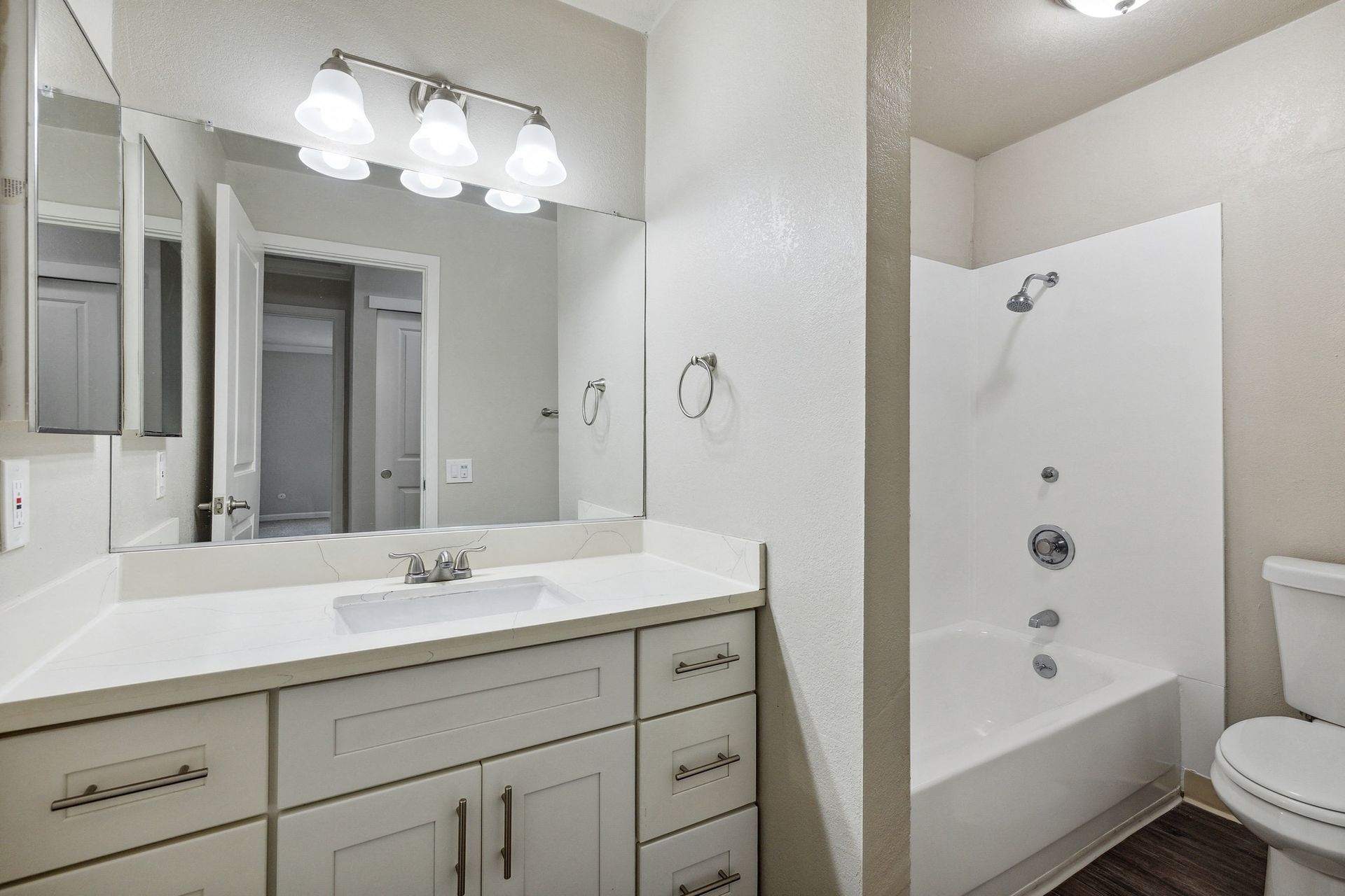 Bathroom with white vanity, large mirror, and a tub/shower combo.