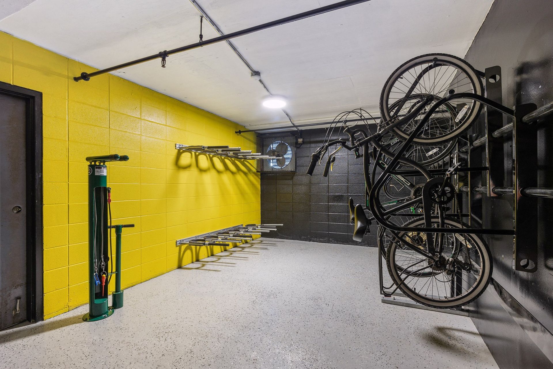 Bike storage room with bicycles mounted on a rack next to a yellow wall.