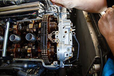 A person is working on a car engine with a wrench.