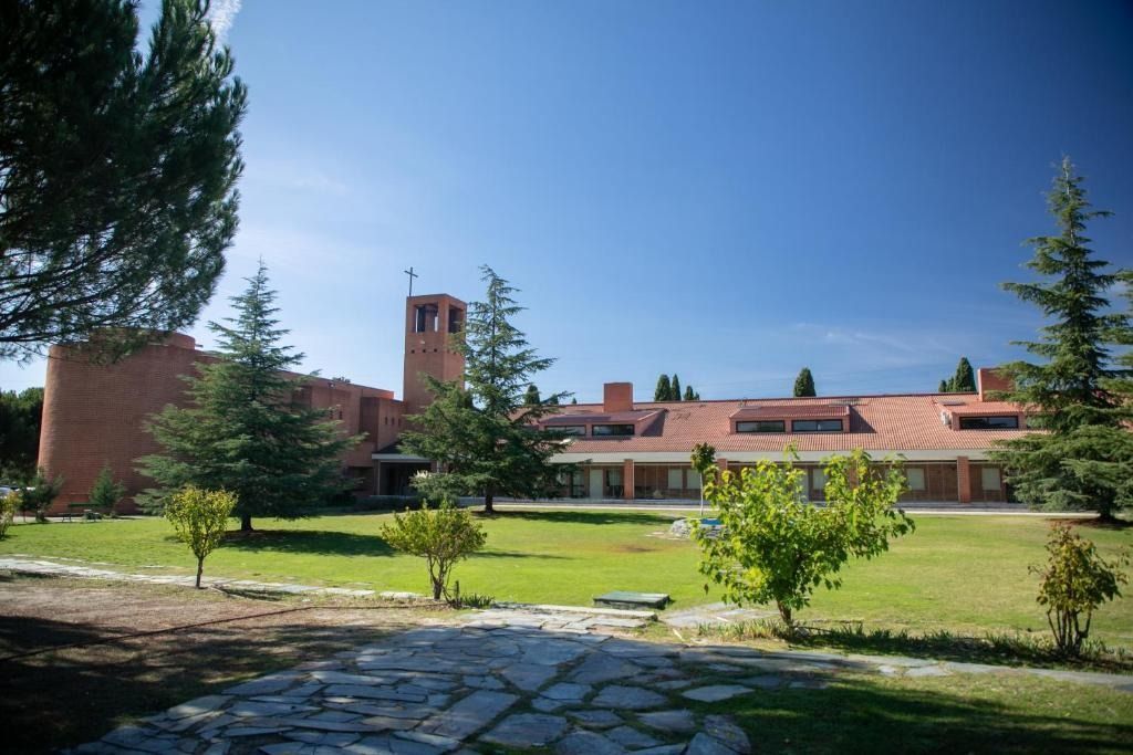 Red brick building with tower on a green lawn under a bright blue sky, trees in view.