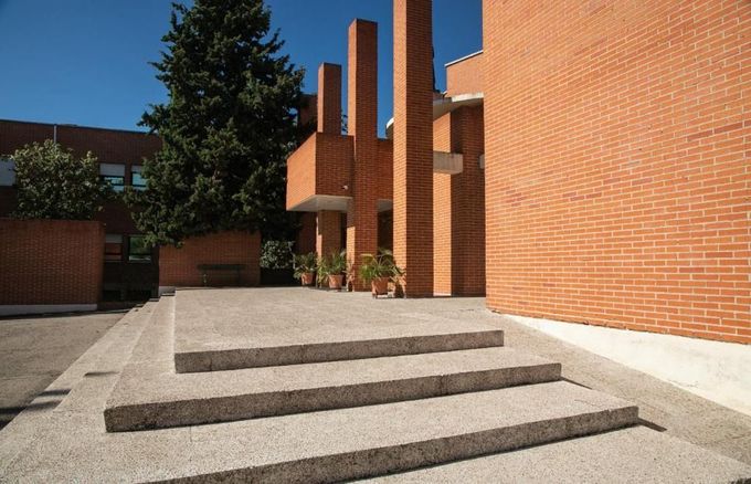 Brick building entrance with three stone steps, pillars, and a clear blue sky.
