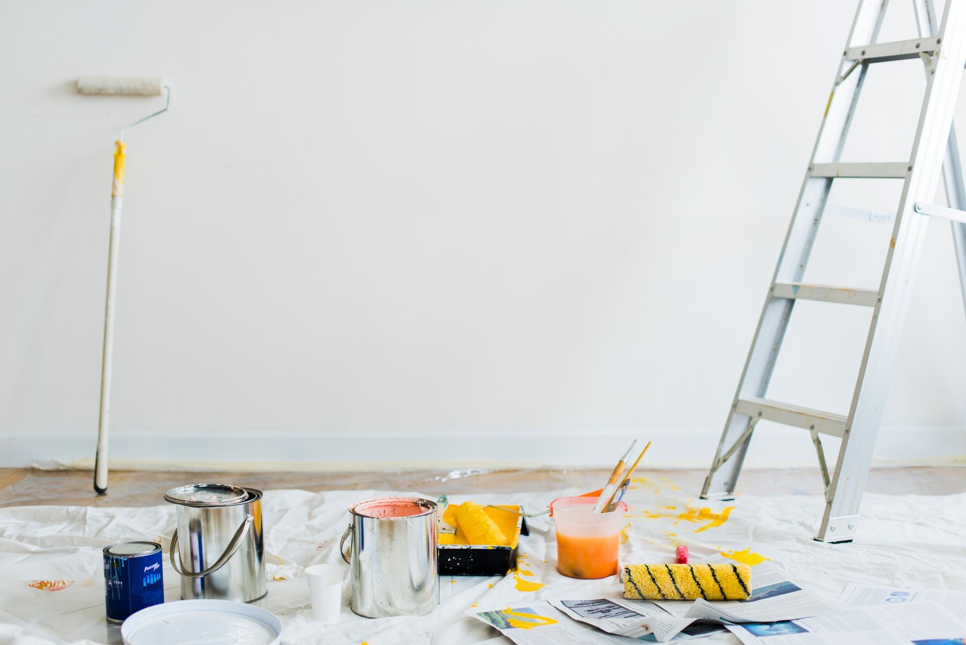 A room is being painted with paint , brushes , and a ladder.