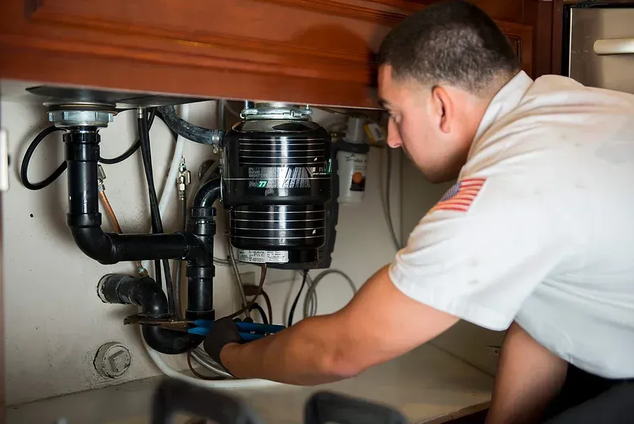 A man is fixing a garbage disposal in a kitchen.